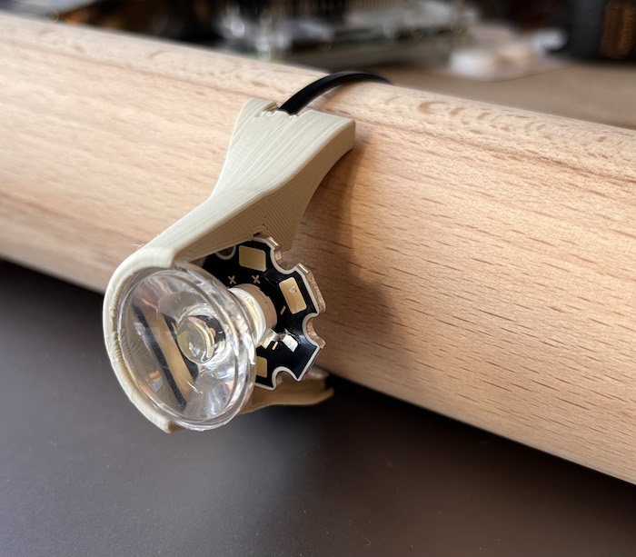An image of an LED and a lense mounted to a tube in a 3D printed case. The case is split in half so you can see what's inside.