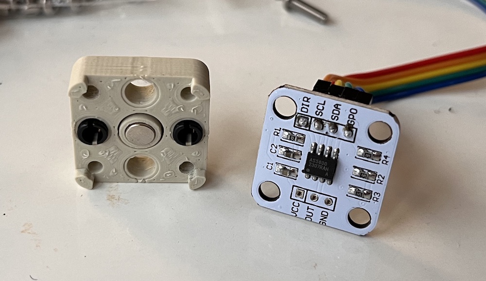 The pieces of the mount for encoder board split. One half holds the magnet with an adapter for lego shafts and the other holds the PCB with the endcoder on it.