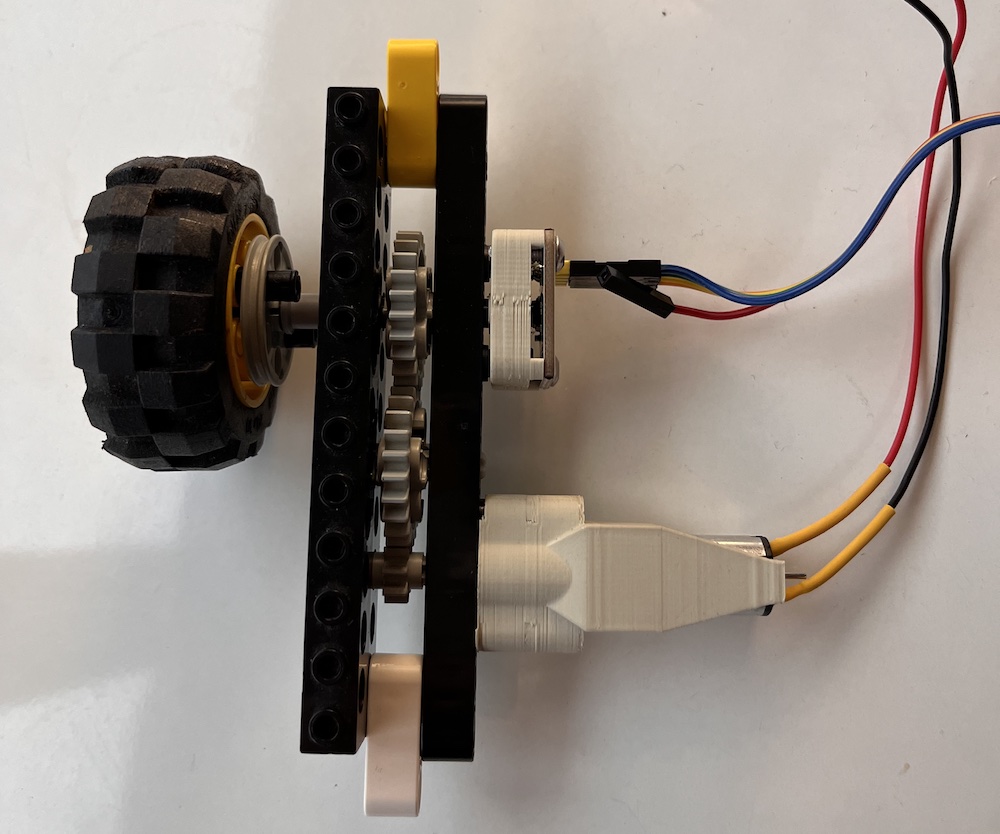 The encoder and a custom lego motor mounted to a beam with a gear train linking them together and to a lego wheel.